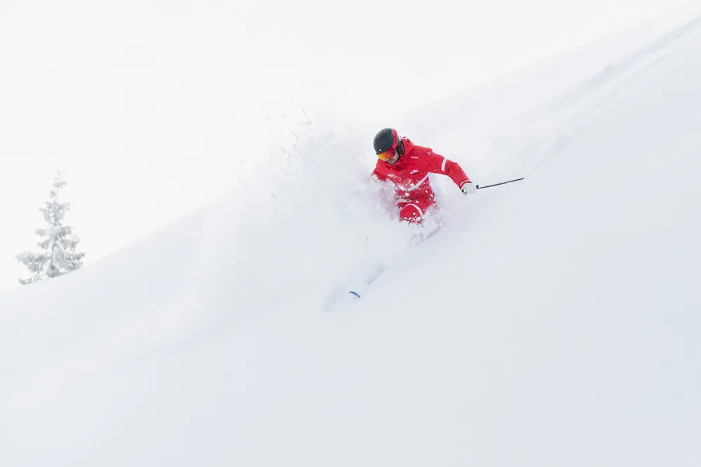 Skilehrer der Skischule Rot-Weiss-Rot im Tiefschnee mit aufstiebendem Pulverschnee