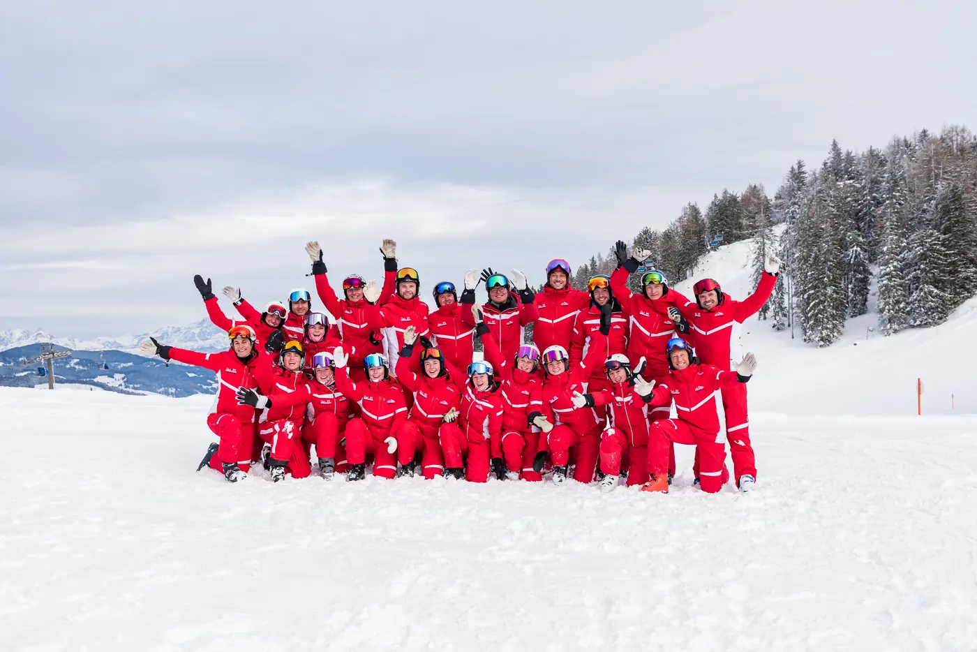 Das Team der Skischule Rot-Weiss-Rot Alpendorf in roten Skianzügen im Schnee